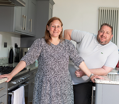 Vince and his partner standing in the kitchen smiling at the camera