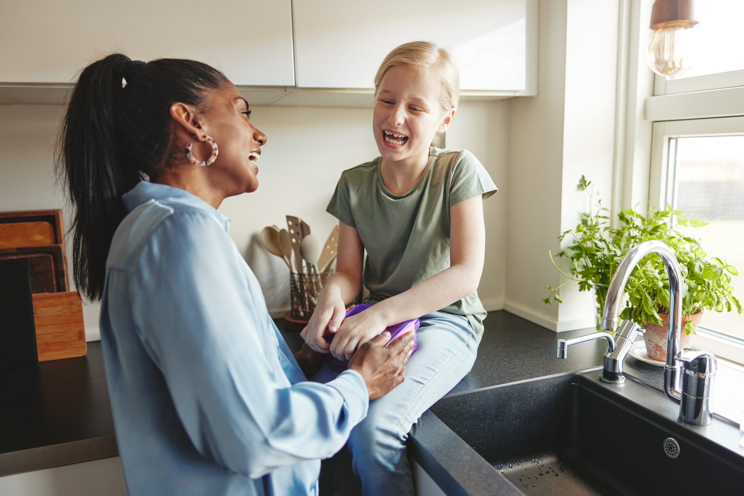 Foster carer and fostered child laughing in their kitchen