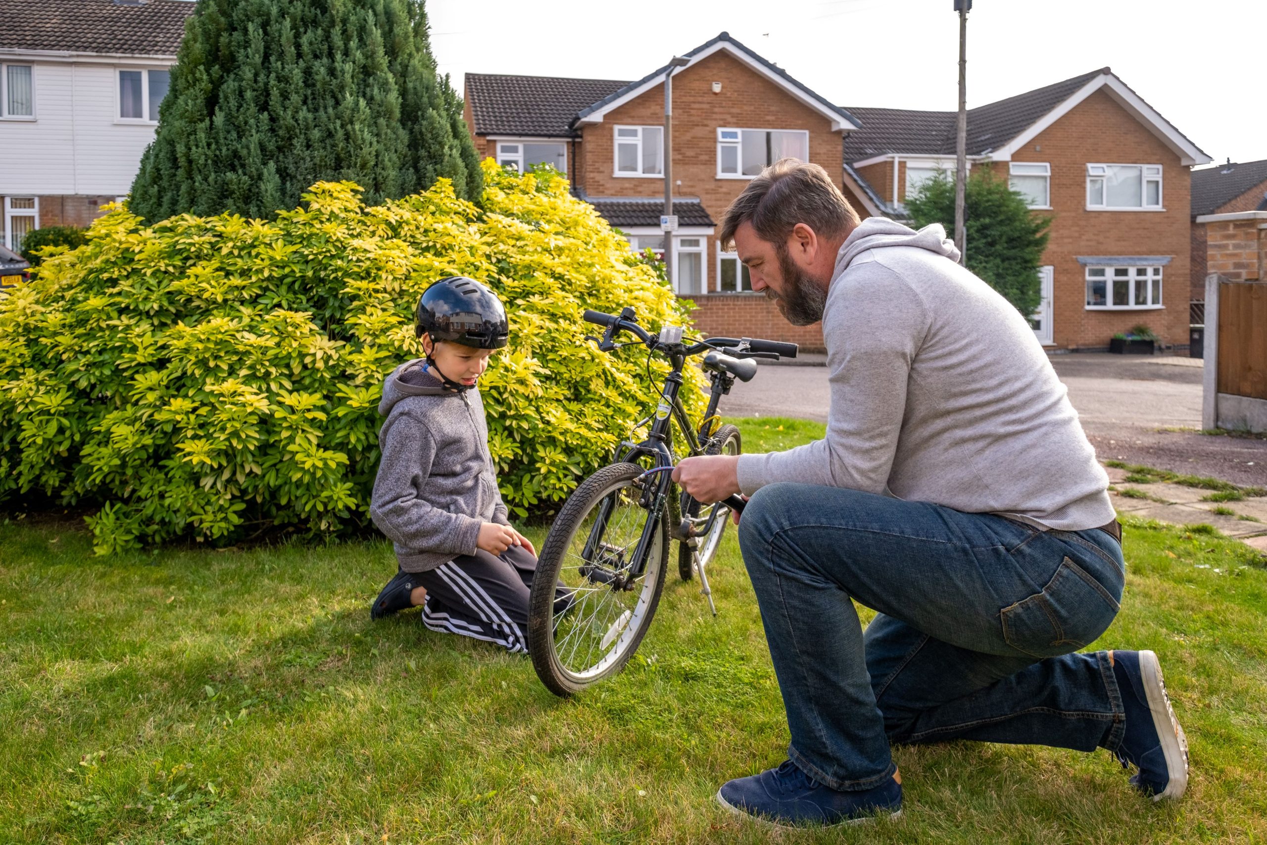 man helping his foster child repair his bike