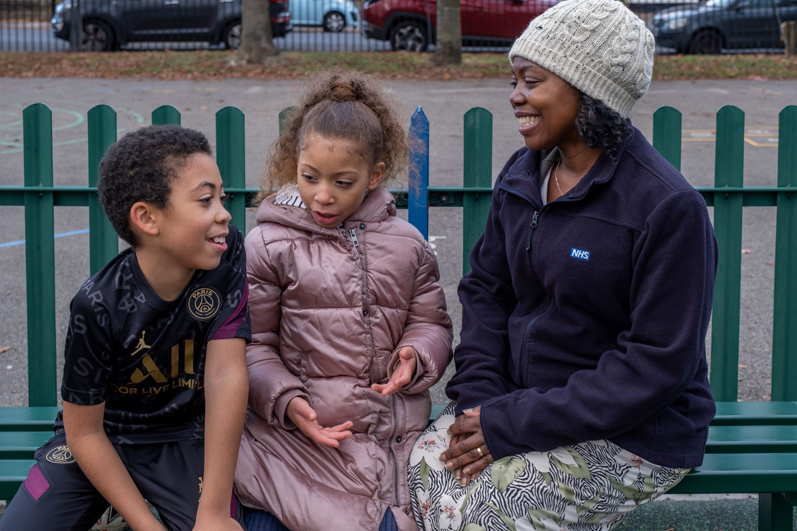 woman wearing an NHS jumper sitting on on a bench with her foster children