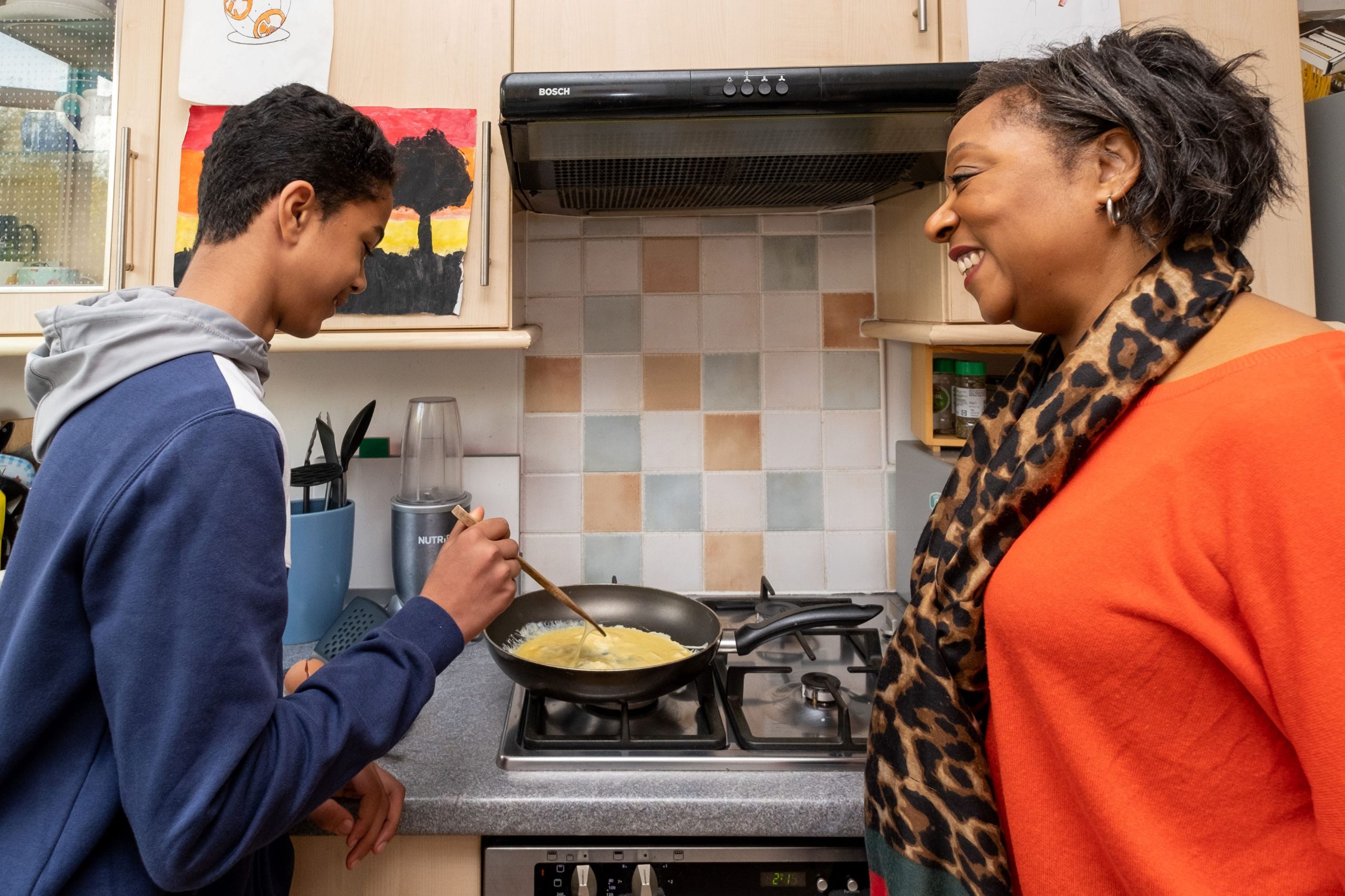 woman teaching her foster child how to cook eggs