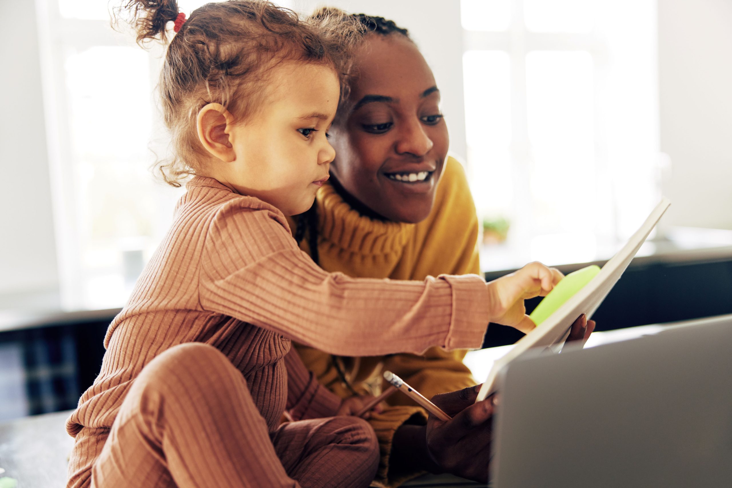 a foster carer and their toddler child in care watching the screen of a laptop together