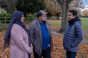 a fostering couple and a young person in a garden talking and smiling with each other