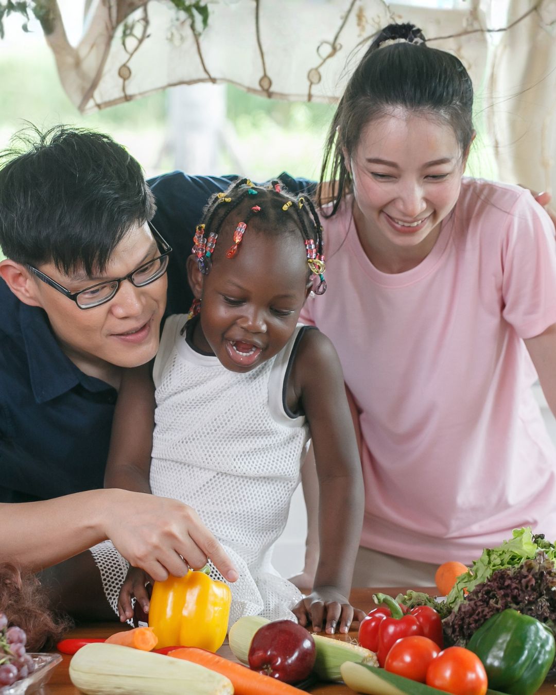 A fostering couple teaching their foster child about fruit and vegetables