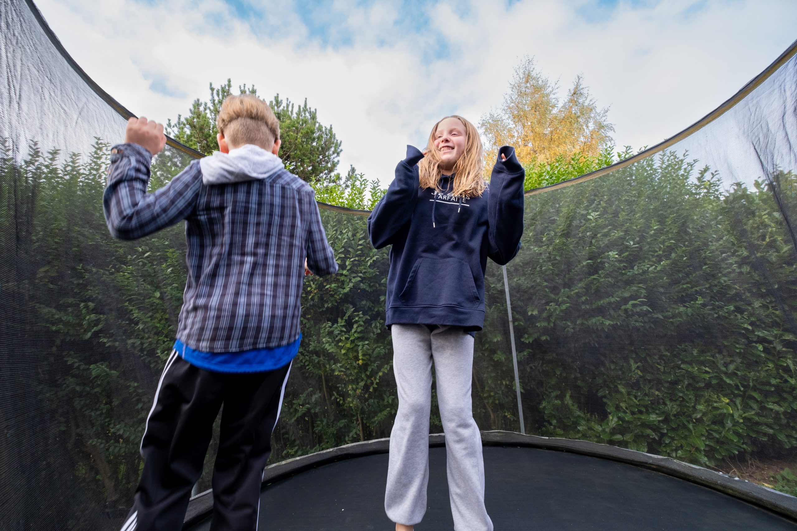 two children jumping happily on an outdoor trampoline