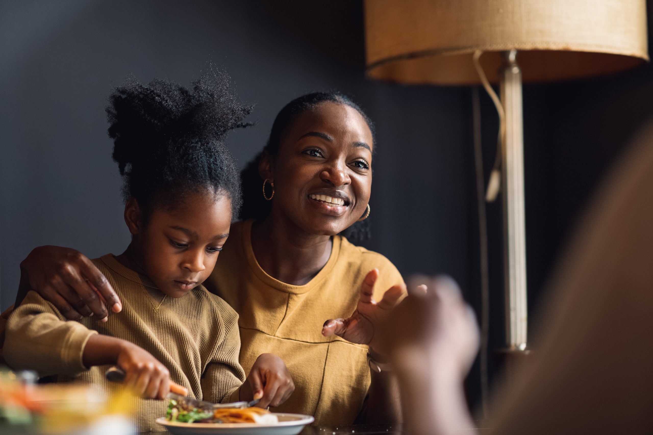 foster carer with a foster child on their lap who's eating from a plate