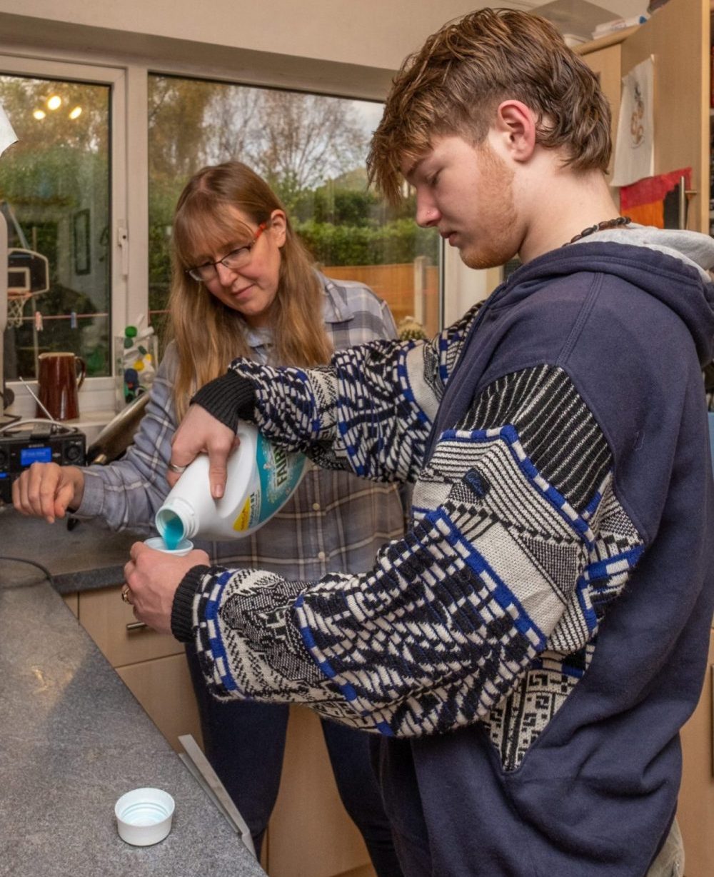 foster carer teaching their foster young person how to do loundry